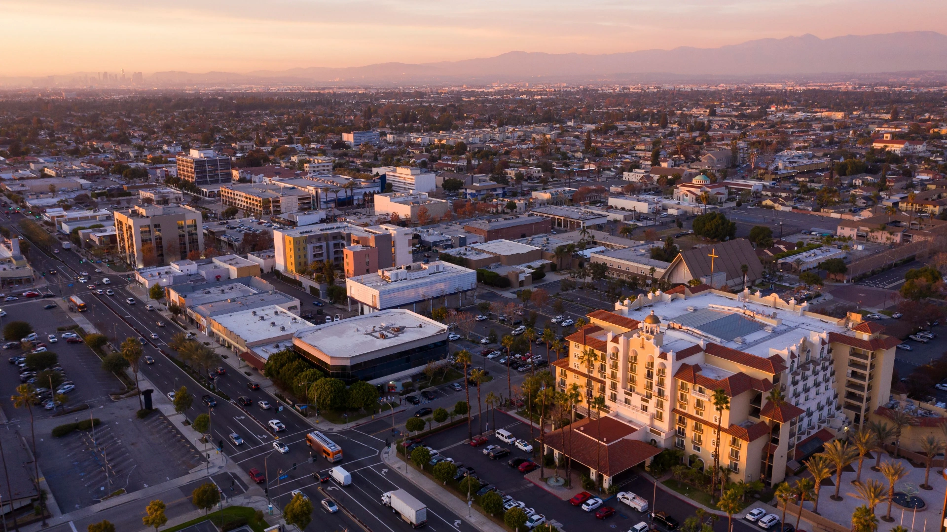 Aerial view of Downey, California at sunset with the downtown Los Angeles skyline in the distance